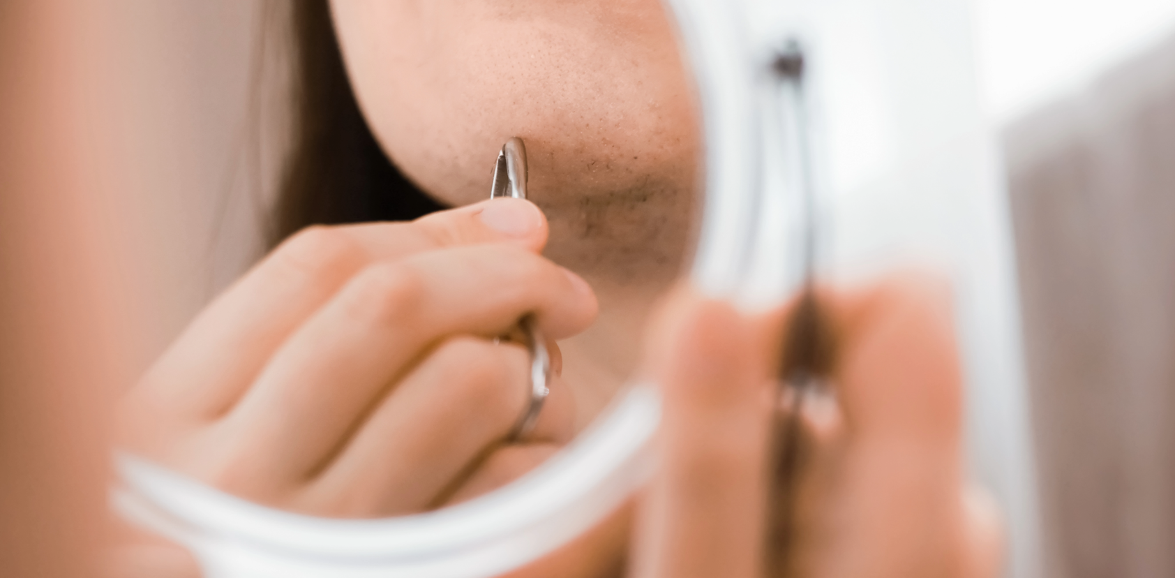 PCOS - Frau zupft Haare am Kinn aus