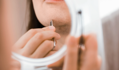 PCOS - Frau zupft Haare am Kinn aus